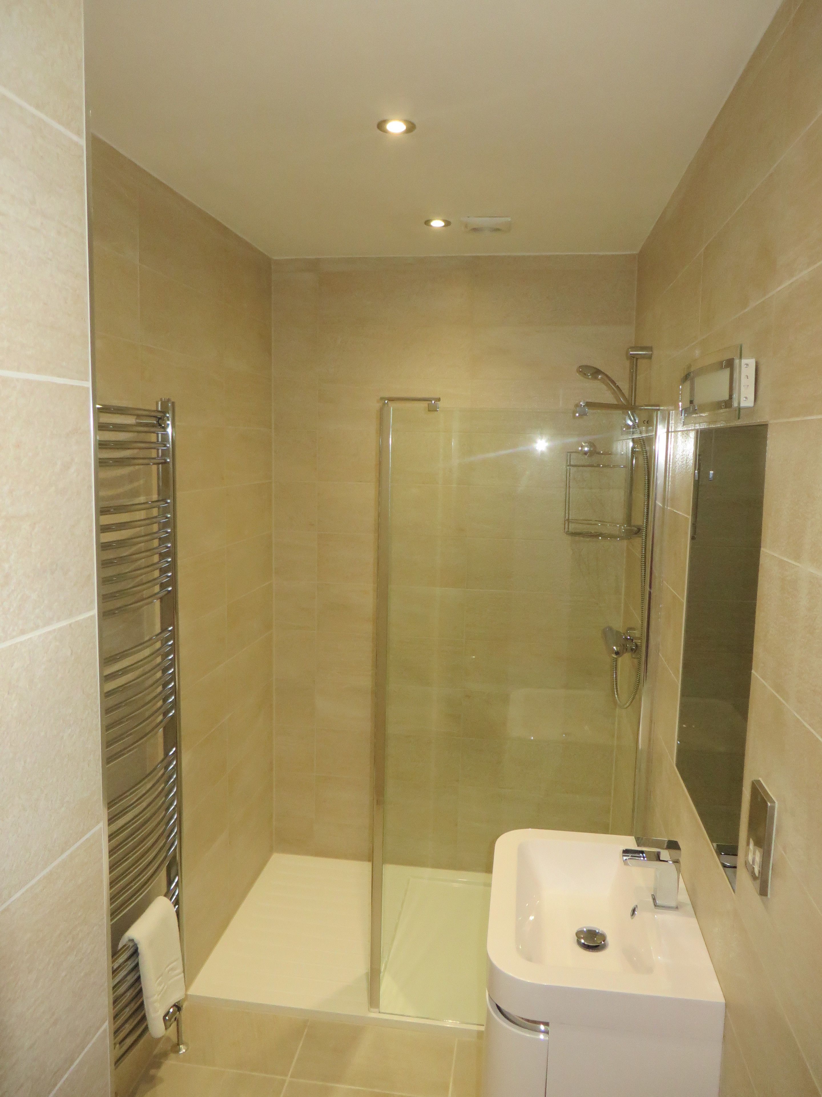 Un baño moderno con ducha de vidrio, lavabo blanco y barra para toallas.