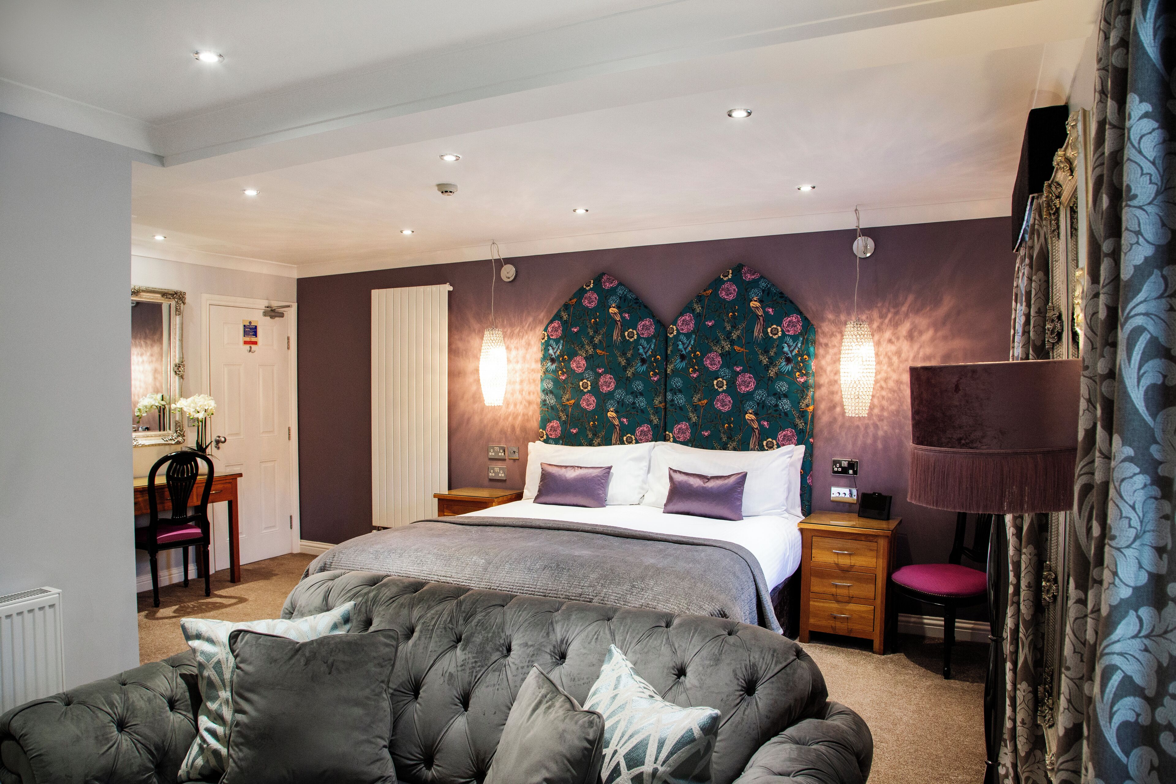 A bedroom with a large bed, a tufted headboard, bedside tables, a lamp, and a chair.