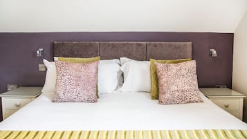 A neatly made bed with patterned pillows, a headboard, and bedside tables with lamps.