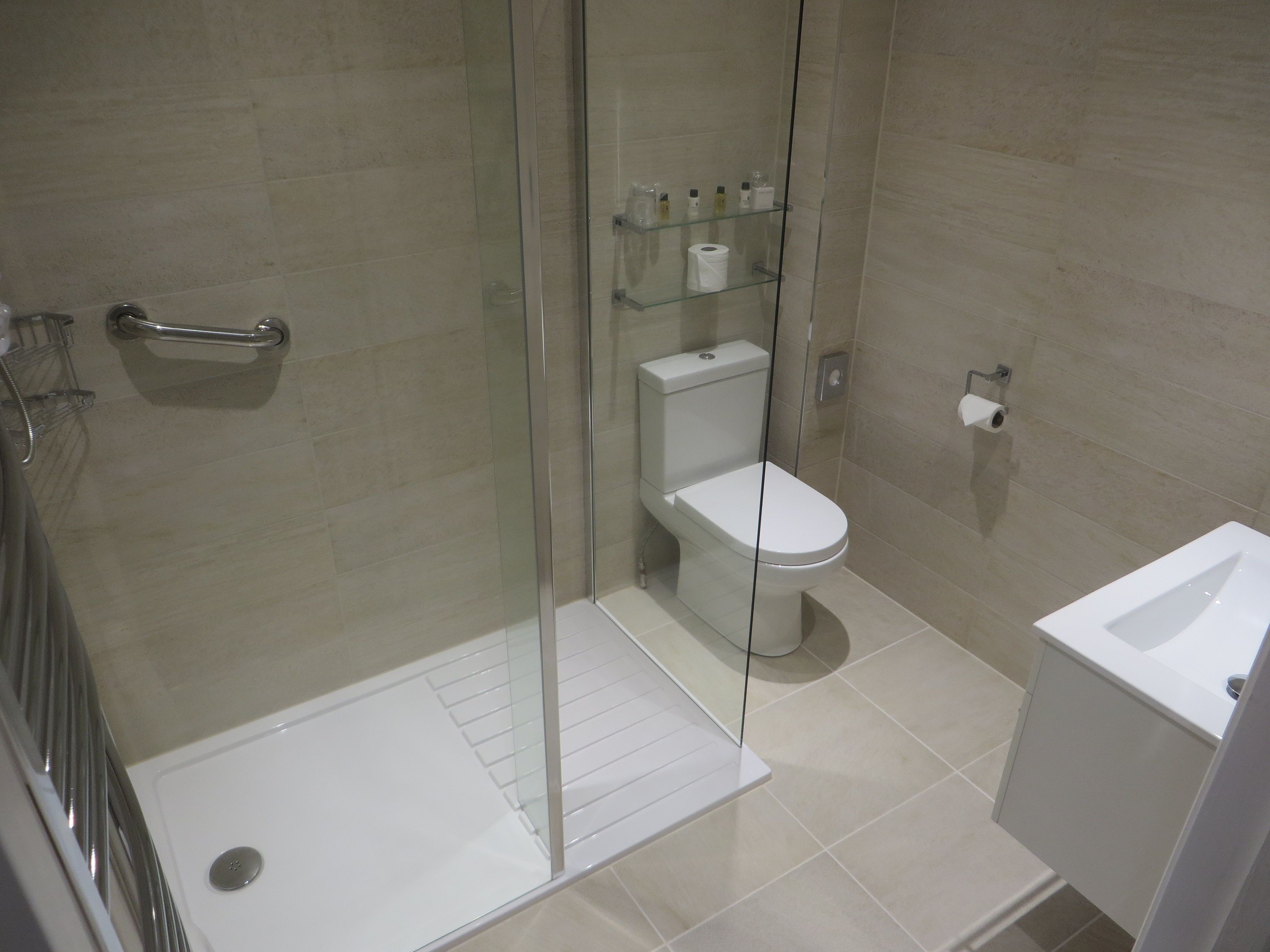 A modern bathroom with a glass-enclosed shower, a toilet, and a sink.
