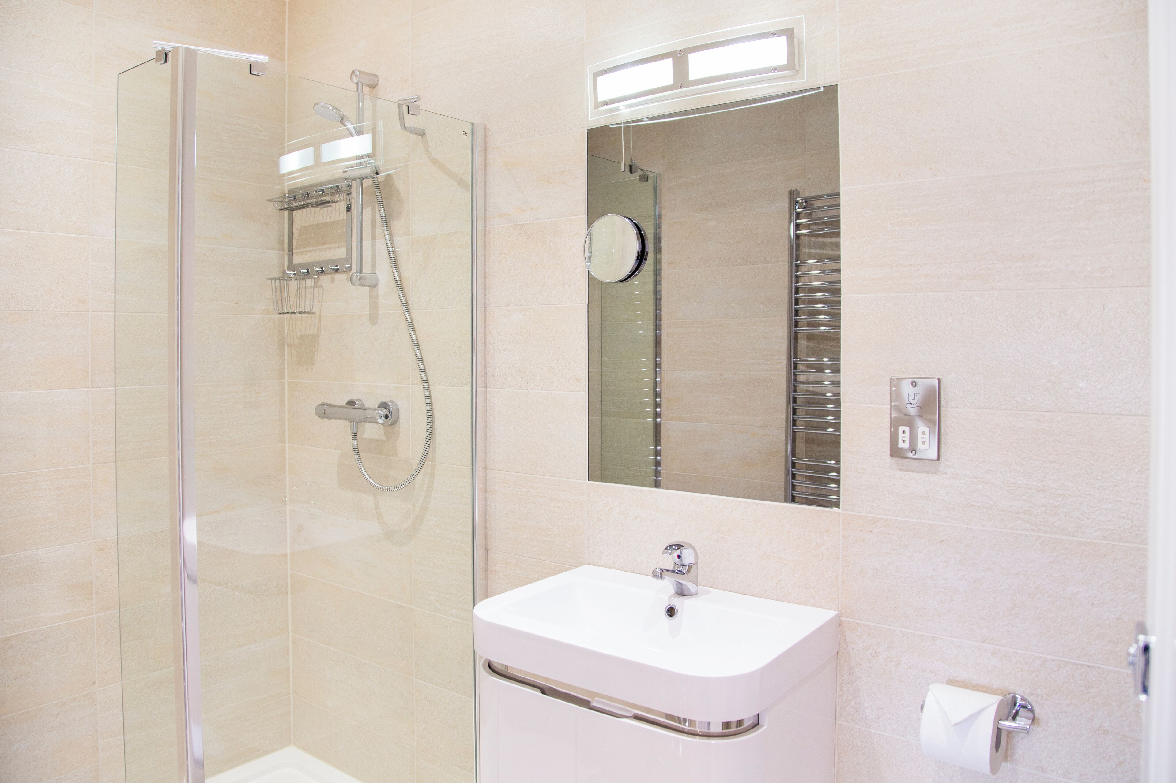 Un baño moderno con cabina de ducha de vidrio, un lavabo blanco y un espejo sobre el lavabo.