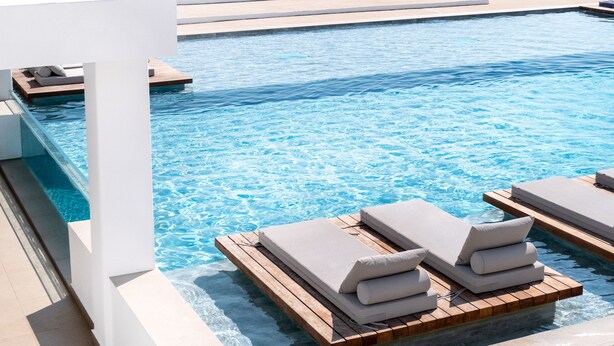 A poolside area with lounge chairs and a view of the sea.