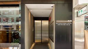 Corredor que leva a um elevador, com uma placa indicando "WiFi Boutique Hotel".