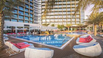 Una piscina al aire libre, sombrillas, sillones reclinables de piscina