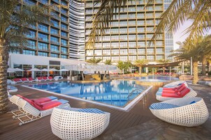 Una piscina al aire libre, sombrillas, sillones reclinables de piscina