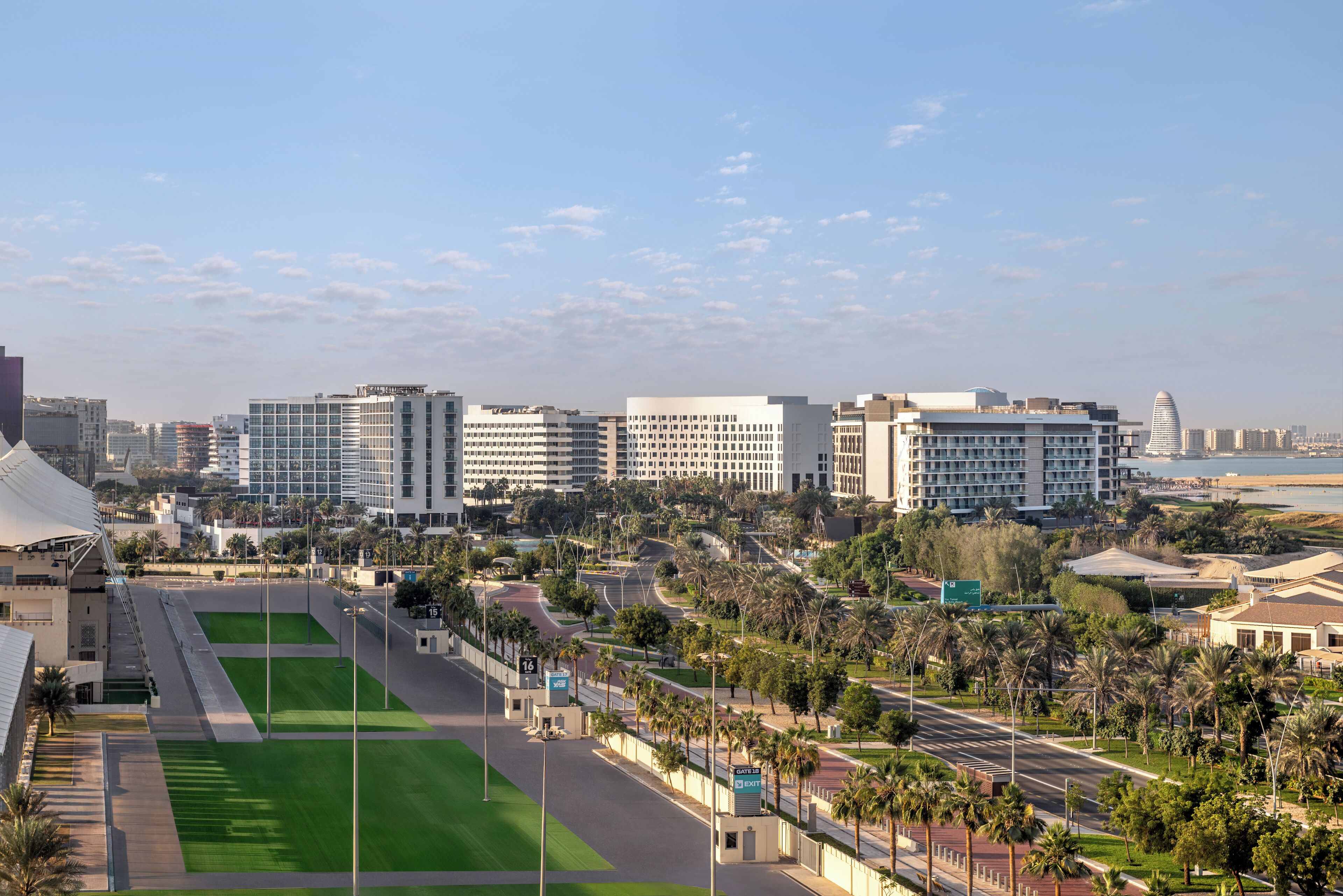 Un paisaje urbano con edificios modernos, un campo deportivo verde y un cielo despejado.