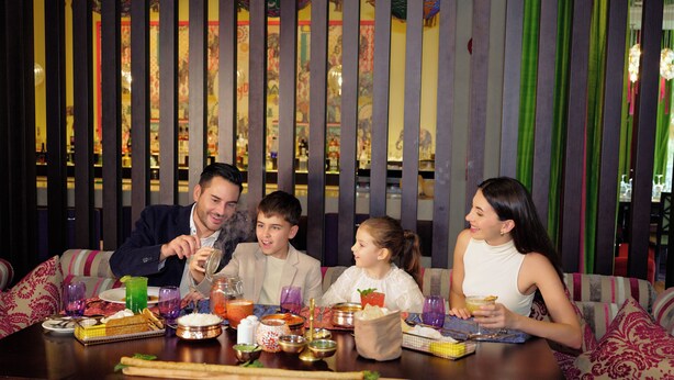 Una familia cenando en una mesa con diversos platos y bebidas.