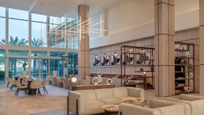 A spacious lobby with a modern design, featuring a large seating area, a well-lit chandelier, and a large bookshelf.