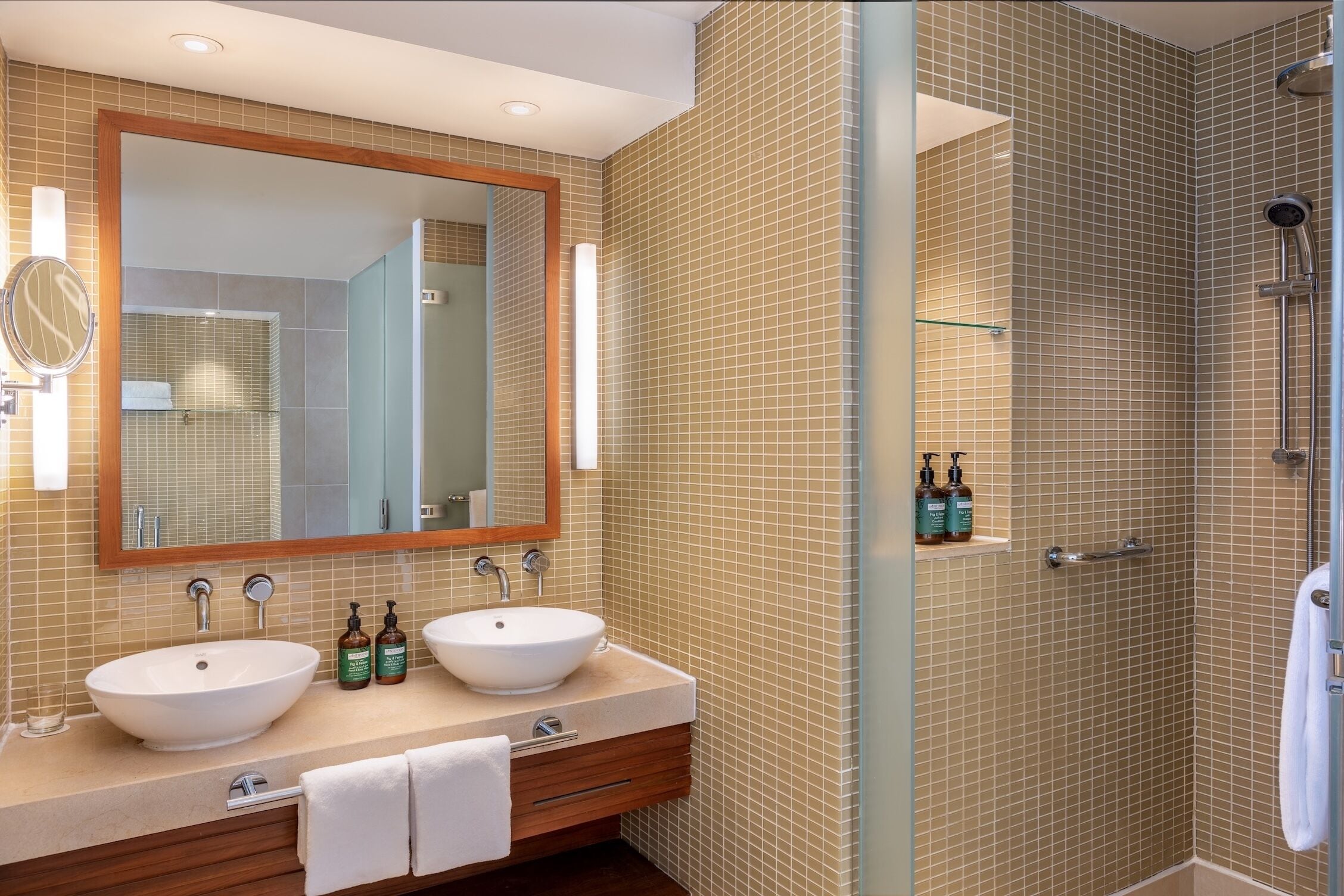 Un baño con dos lavamanos, un espejo grande y una zona de ducha.