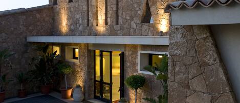 Un edificio de piedra con diseño moderno, con ventanas amplias y una entrada bien iluminada.