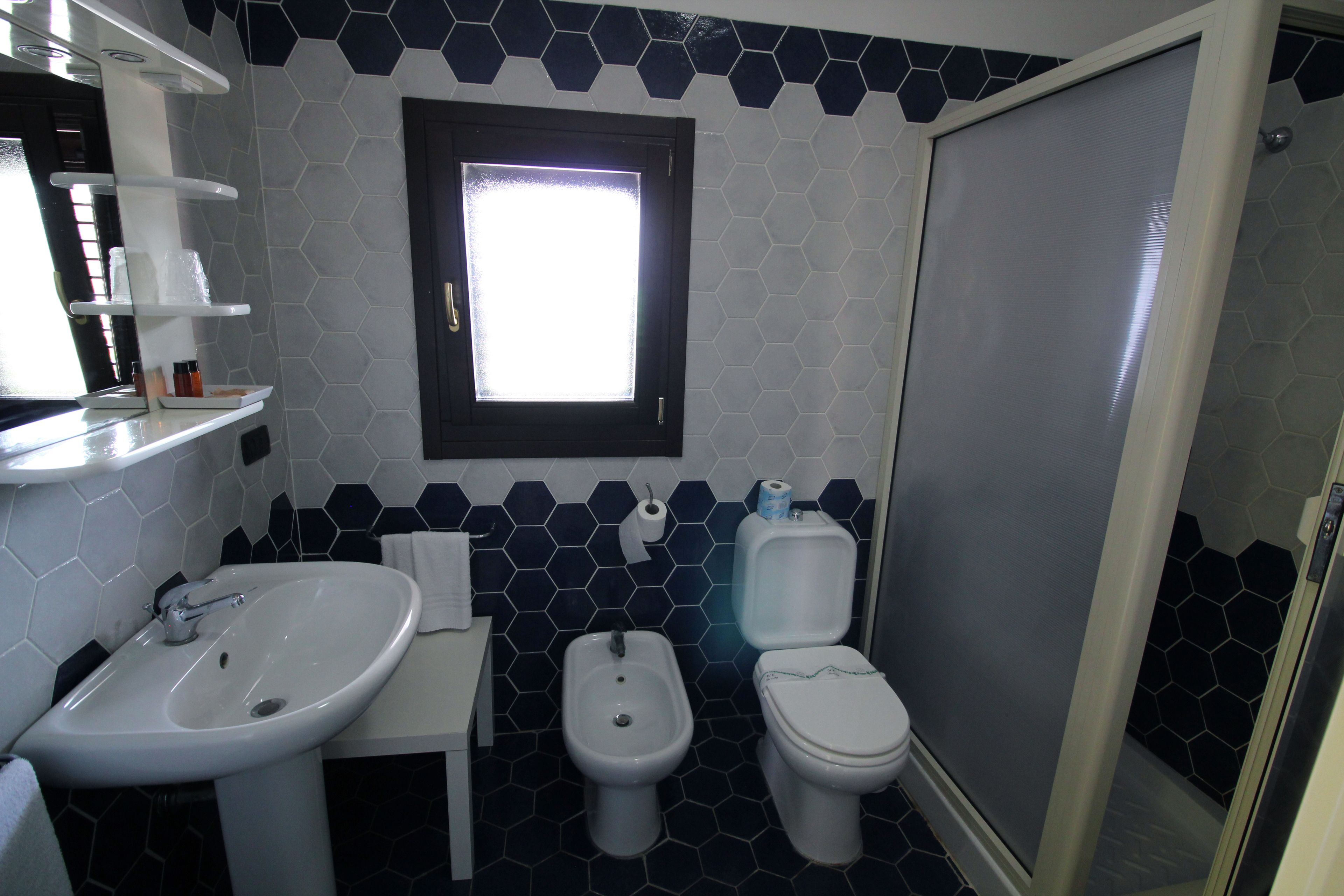 A bathroom with a sink, bidet, toilet, and a window.