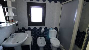 A bathroom with a sink, bidet, toilet, and a window.