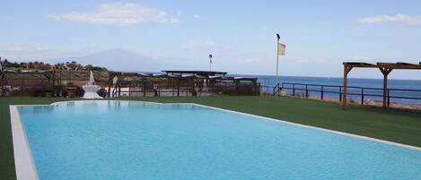 Ein Schwimmbecken mit Blick auf den Ozean und einem Berg im Hintergrund.