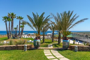 A landscaped outdoor area with palm trees, a pathway, and outdoor seating. - Hotel Residence Capo Campolato (Augusta)