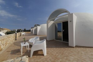 A rooftop terrace with white chairs and a small table, featuring a stone wall and a clear sky. - Hotel Residence Capo Campolato (Augusta)