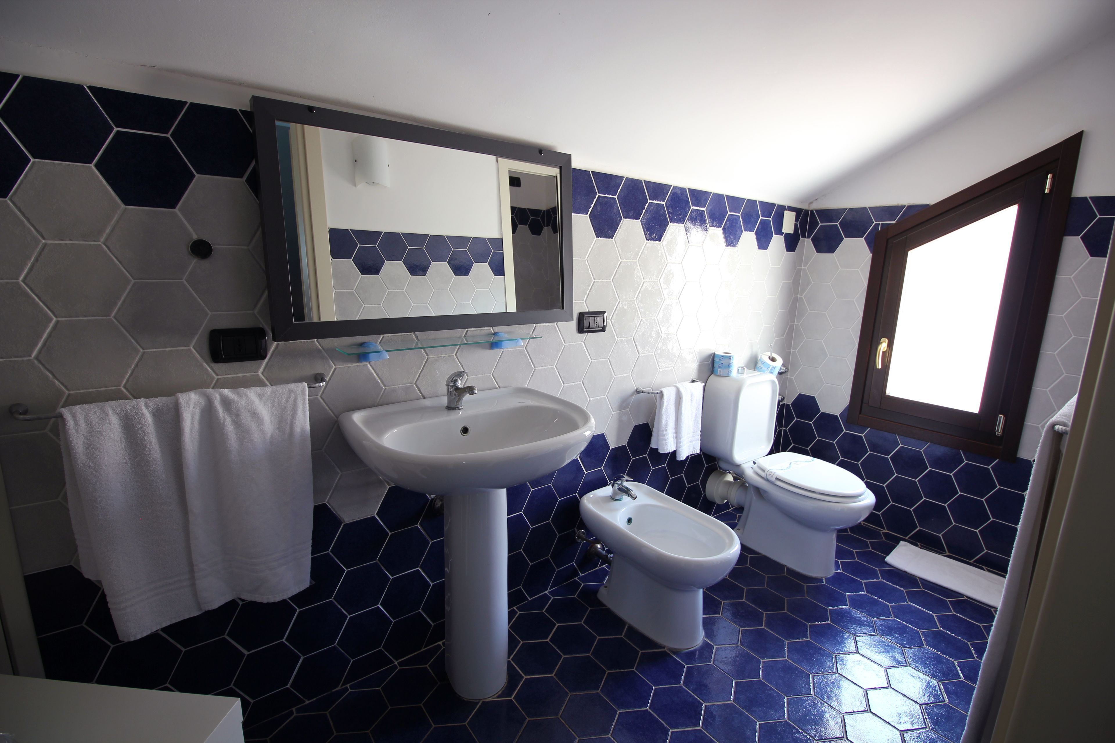 Un baño con lavamanos, bidé, inodoro y espejo.