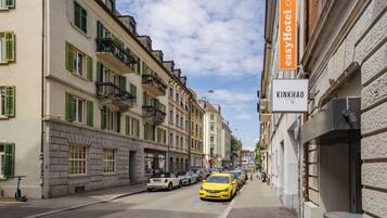Une vue de rue avec un bâtiment portant l’inscription « KINKHAO » et une enseigne pour « easyHotel.com ».
