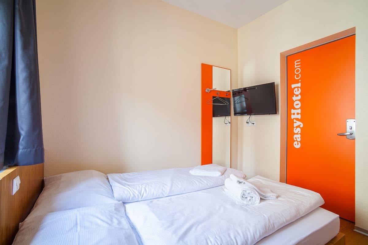 A hotel room with a bed, a TV mounted on the wall, and a door with the hotel's website displayed.