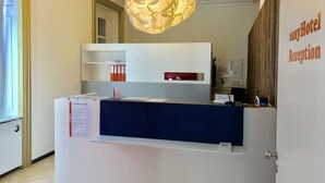 Un comptoir d’accueil avec une plaque nominative, un tableau d’affichage et un luminaire suspendu.