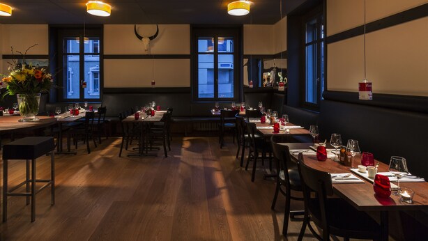 Un restaurant avec des tables et des chaises en bois, disposées pour le service.