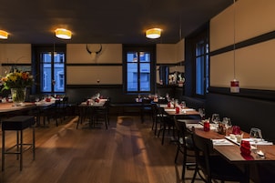 Un restaurante con mesas y sillas de madera, listo para recibir comensales.