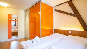 Une chambre à coucher comprenant un lit, un miroir et une porte coulissante donnant sur une salle de bain.