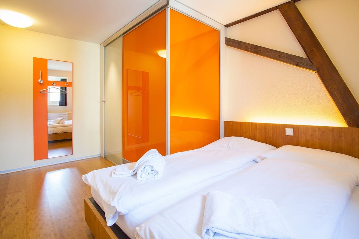 A bedroom with a bed, a mirror, and a sliding door leading to a bathroom.