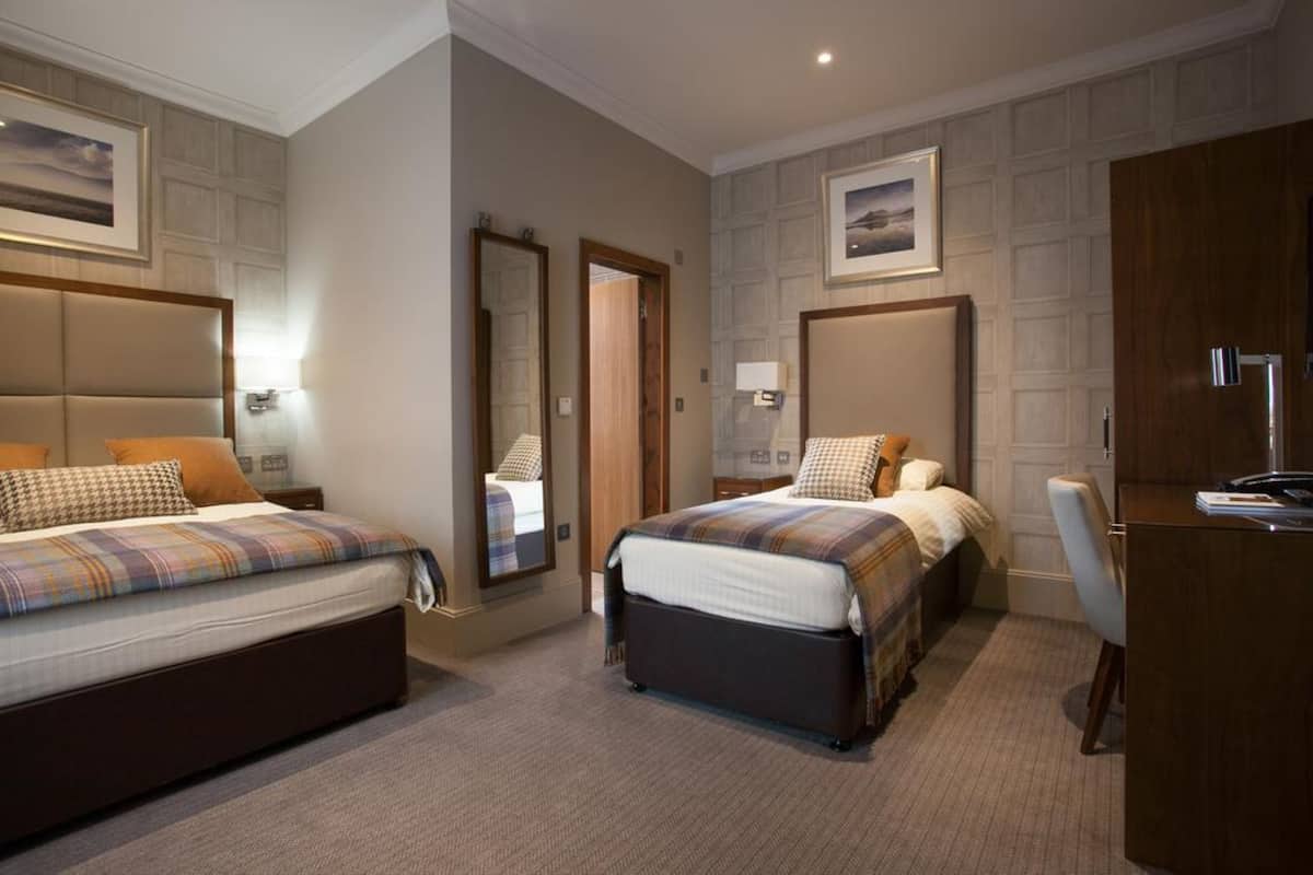 A hotel room with two beds, a desk, and a chair.