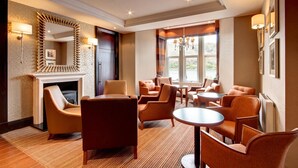 A hotel lobby with a fireplace, comfortable seating, a chandelier, and a large mirror. - Cruachan Hotel (Fort William)