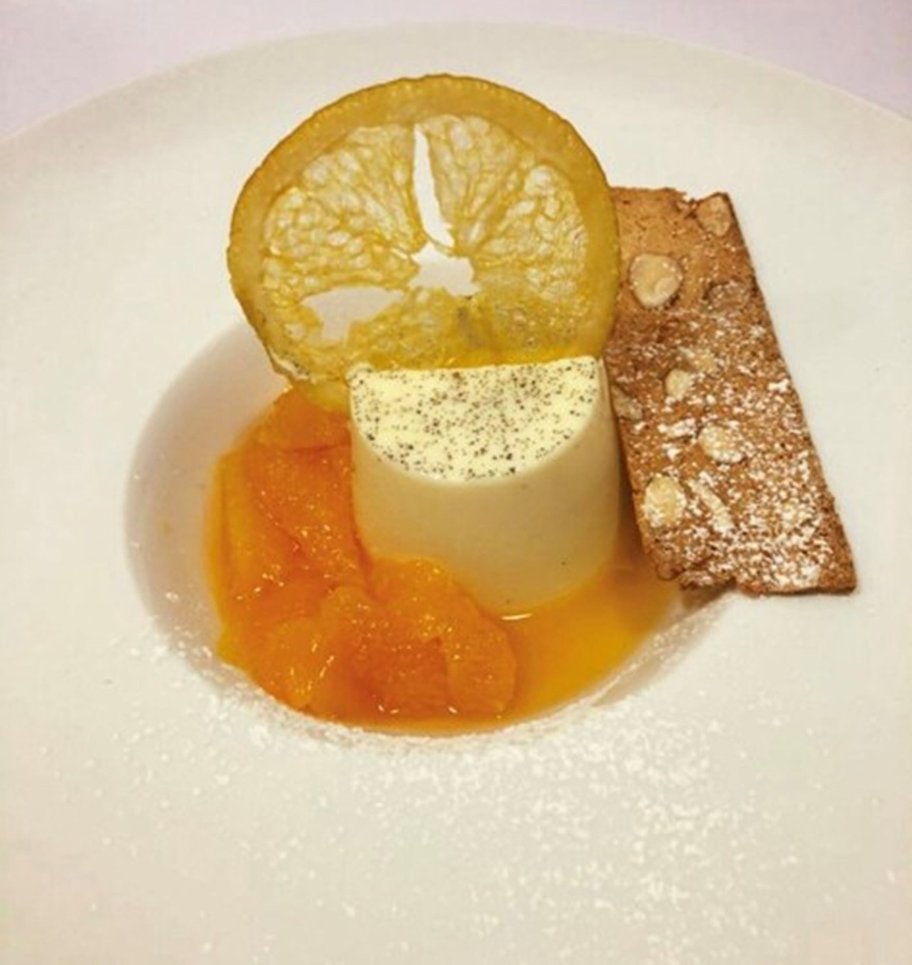 Un dessert agrémenté d’une tranche de citron, accompagné d’une tranche de pain et d’une cuillère de purée d’orange.