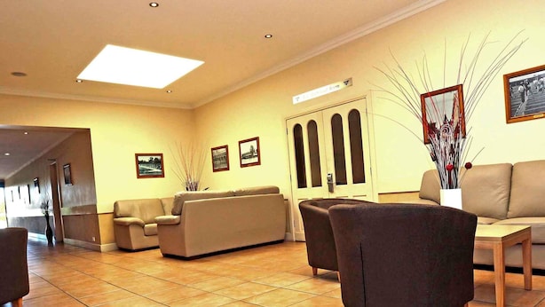 A hotel lobby with a reception desk, seating area, and a door with a sign above it.