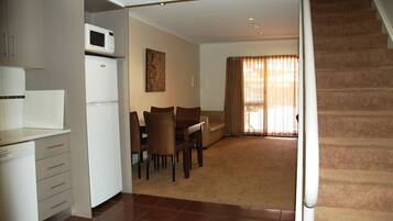 A compact living space with a kitchenette, dining area, and a staircase.