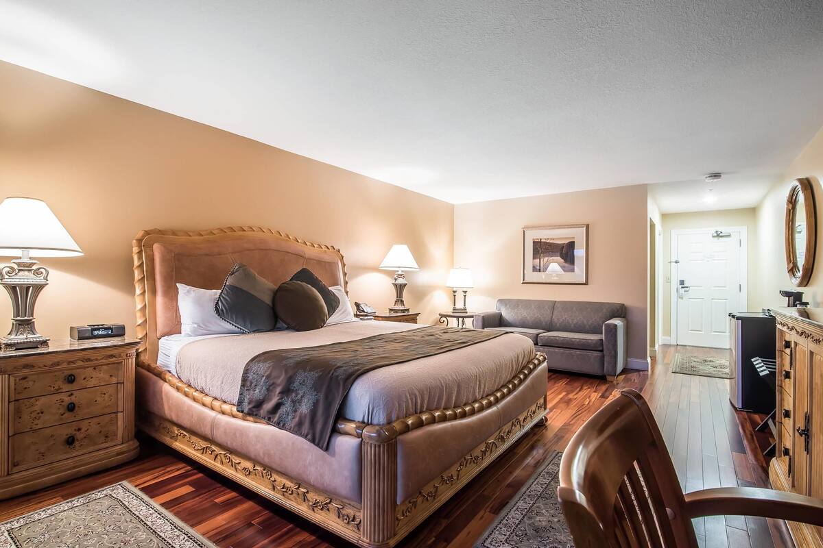A bedroom with a large bed, bedside tables, a chair, a desk, and a wardrobe.
