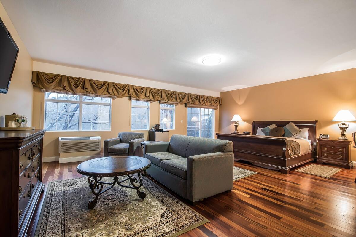 A cozy room with a bed, a sofa, a coffee table, and a TV.