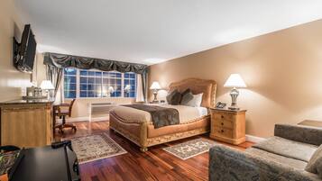 Een hotelkamer met een groot bed, een bureau, een stoel, een bank en een televisie.