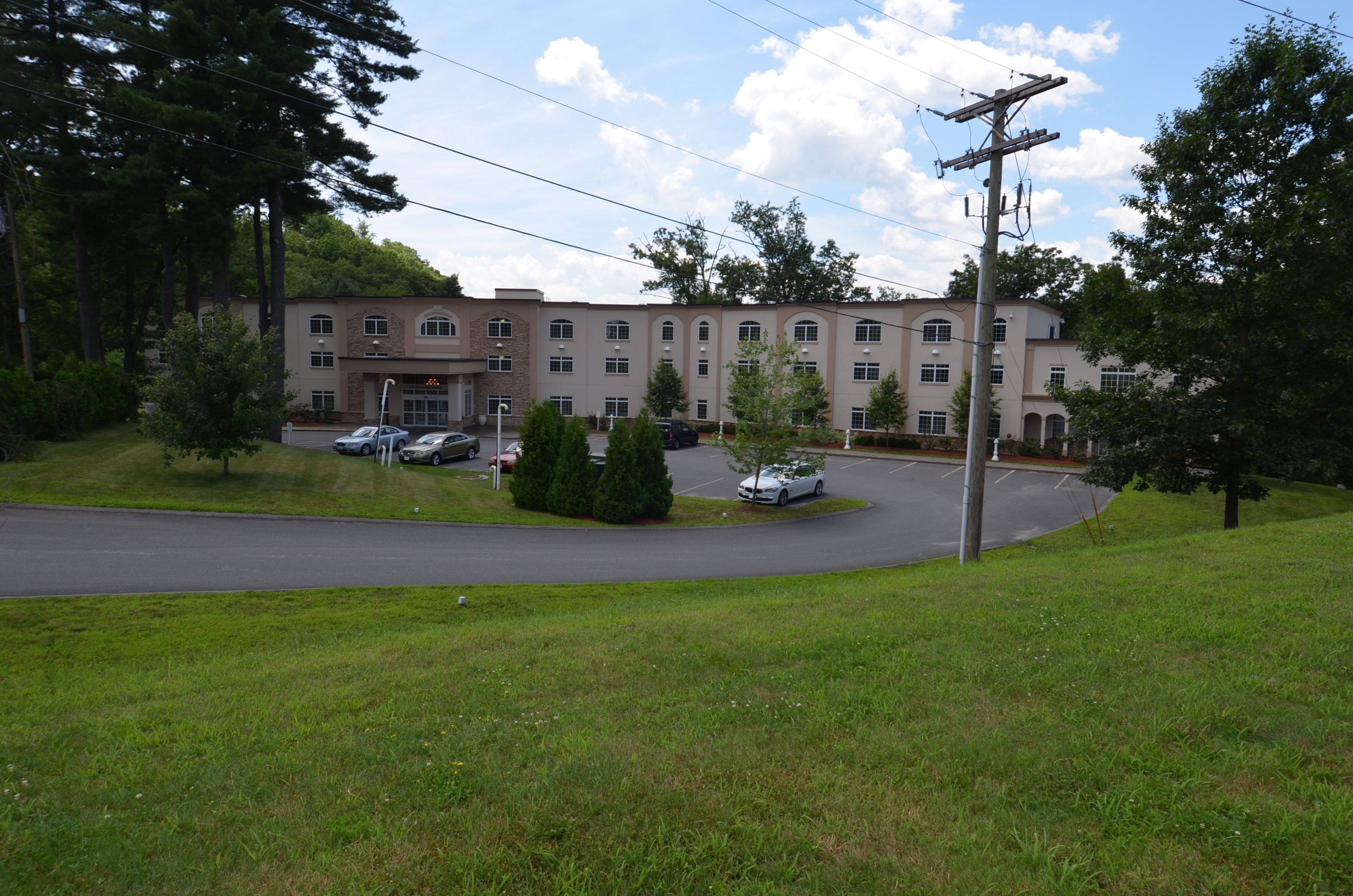 A multi-story building with a parking lot and several cars.