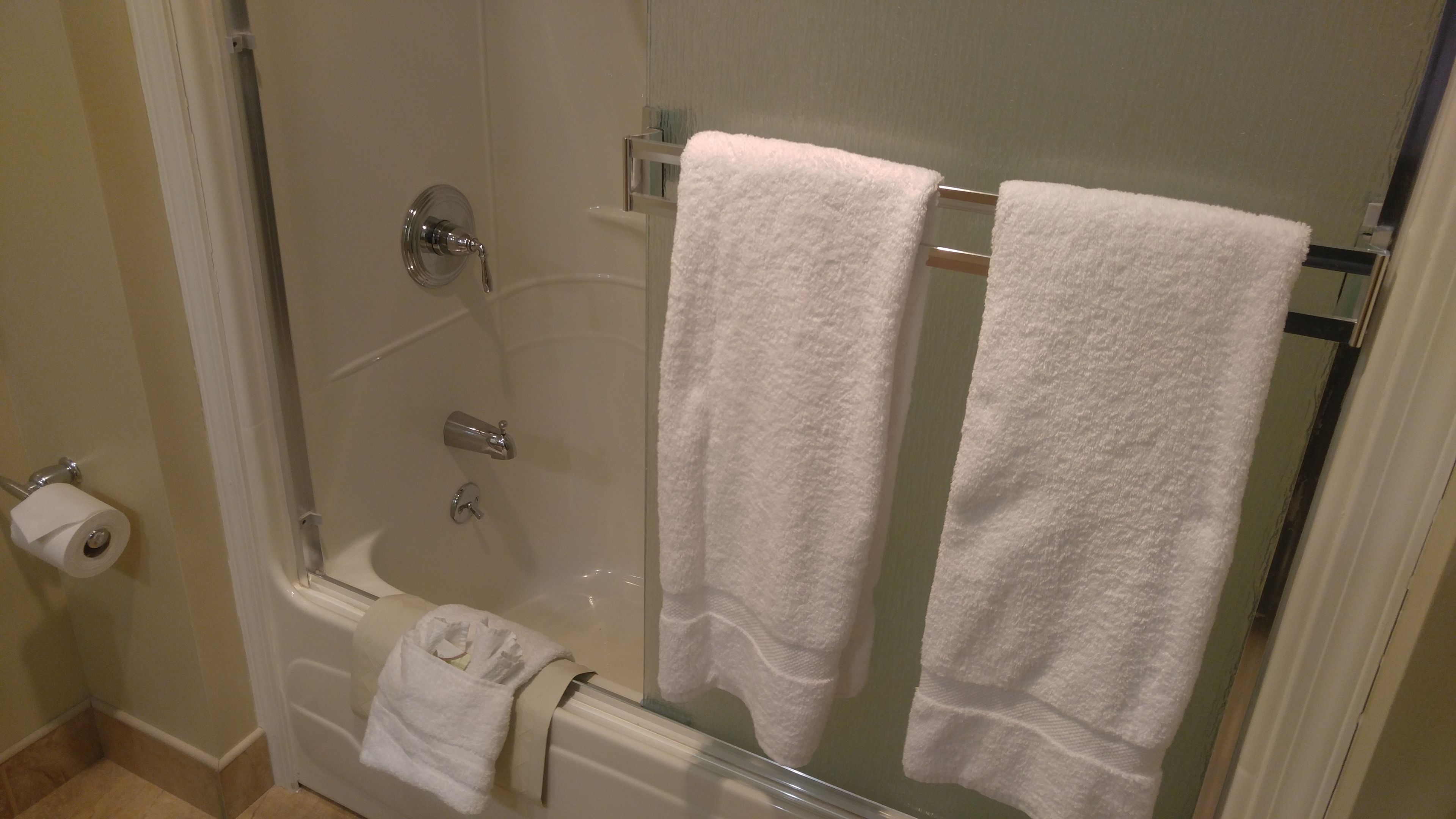 A glass-enclosed shower with a white towel hanging on a rack.