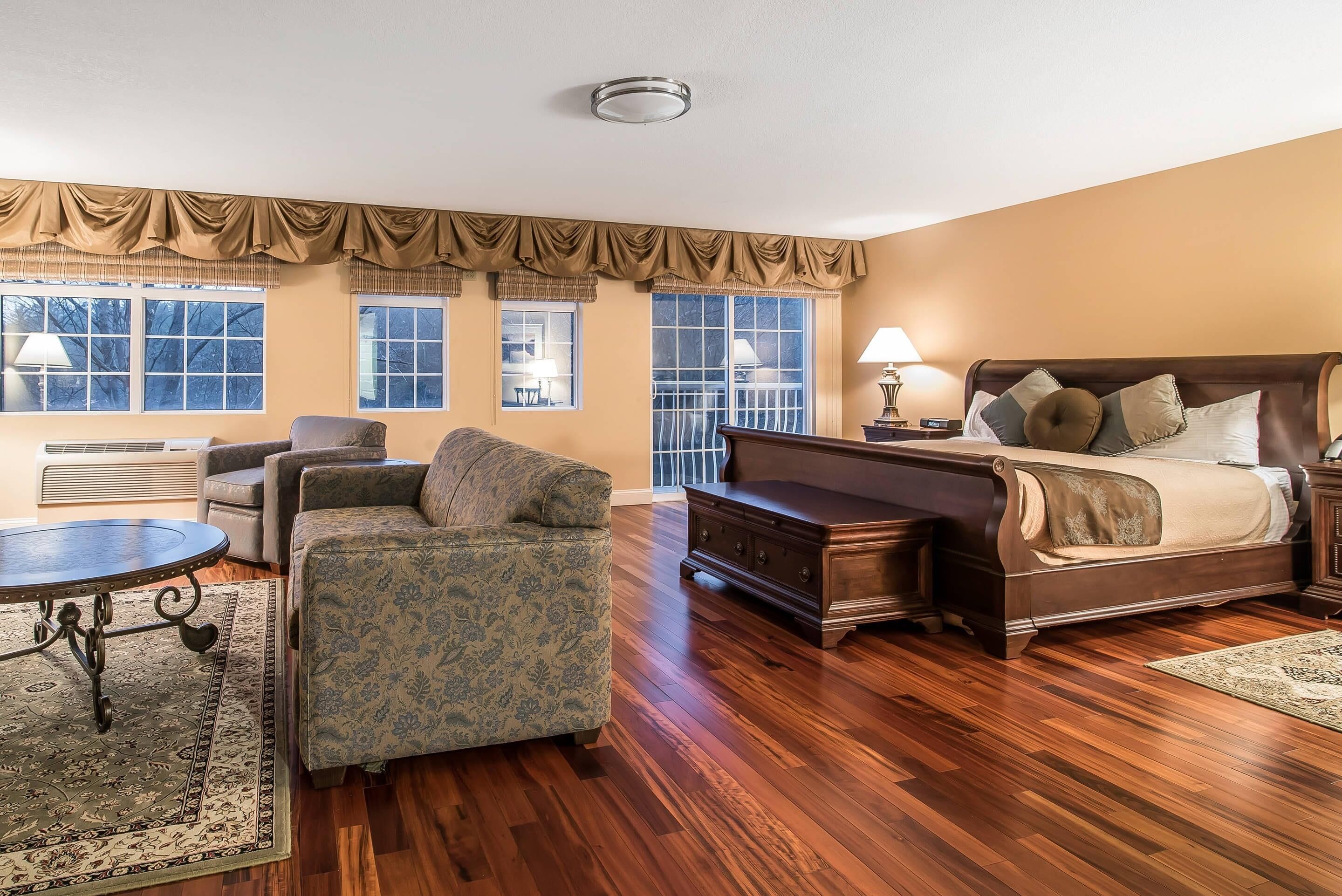 A well-furnished room with a bed, two armchairs, a small table, and a dresser.