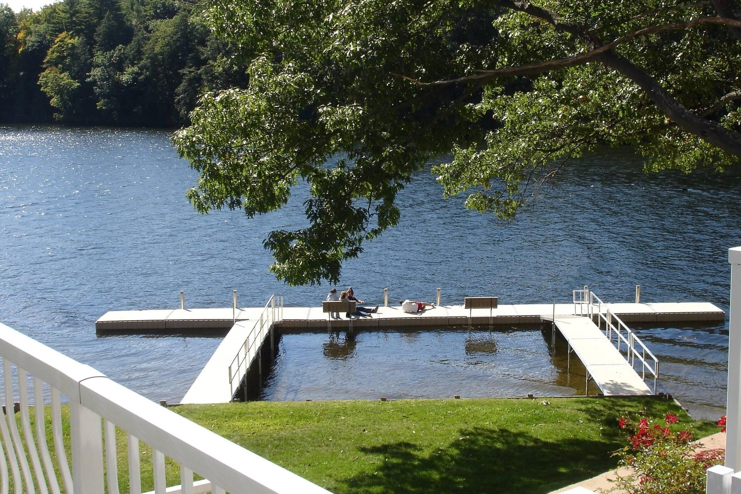 A dock extending into a calm lake, surrounded by lush greenery.