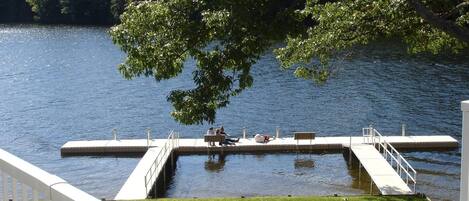 A dock extending into a calm lake, surrounded by lush greenery.