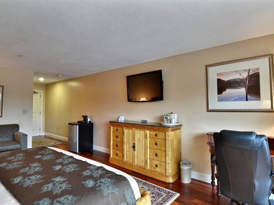 A hotel room with a bed, a desk, a chair, a television, and a framed picture on the wall.