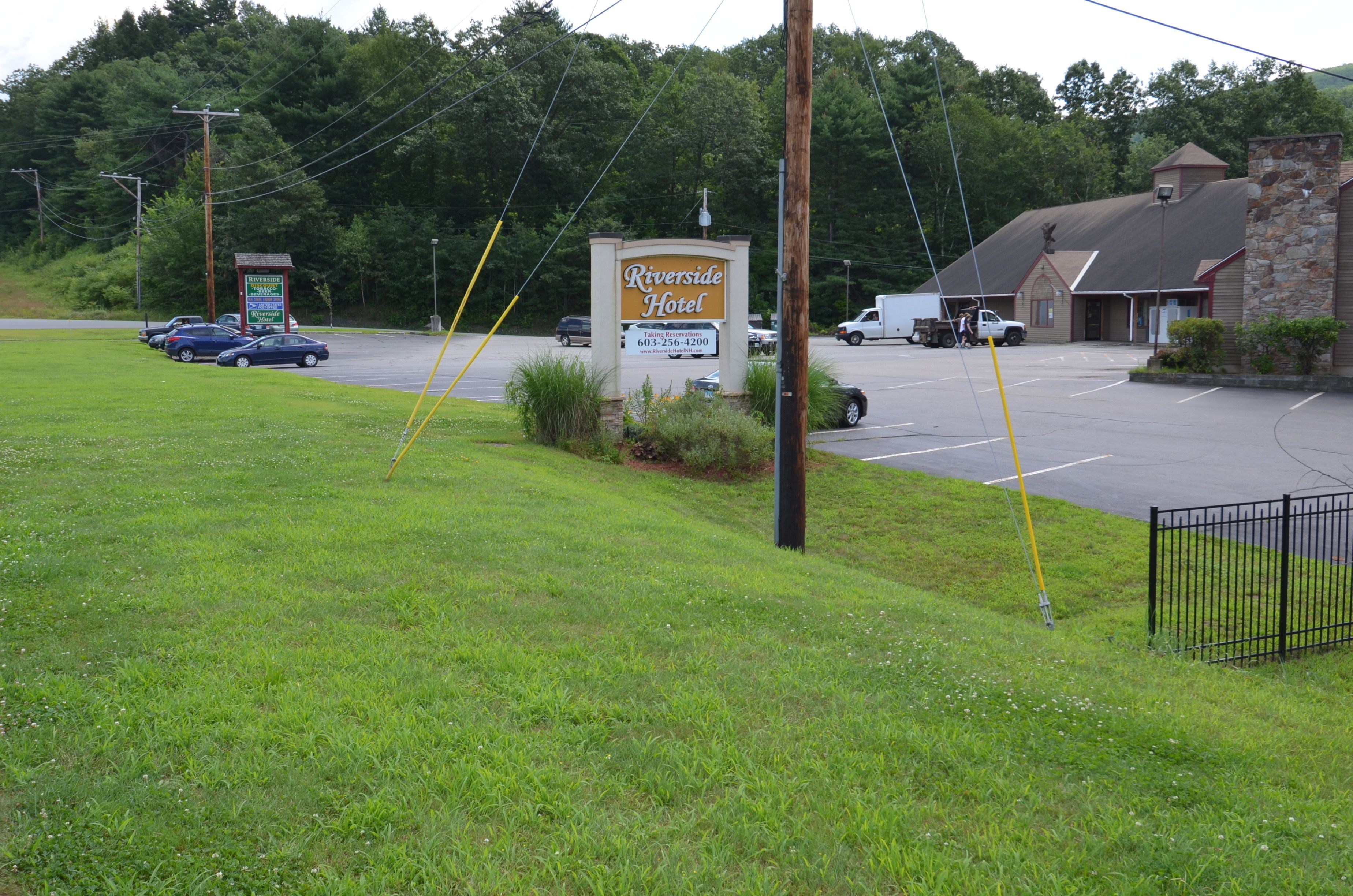 A hotel sign with a parking lot and a building in the background.