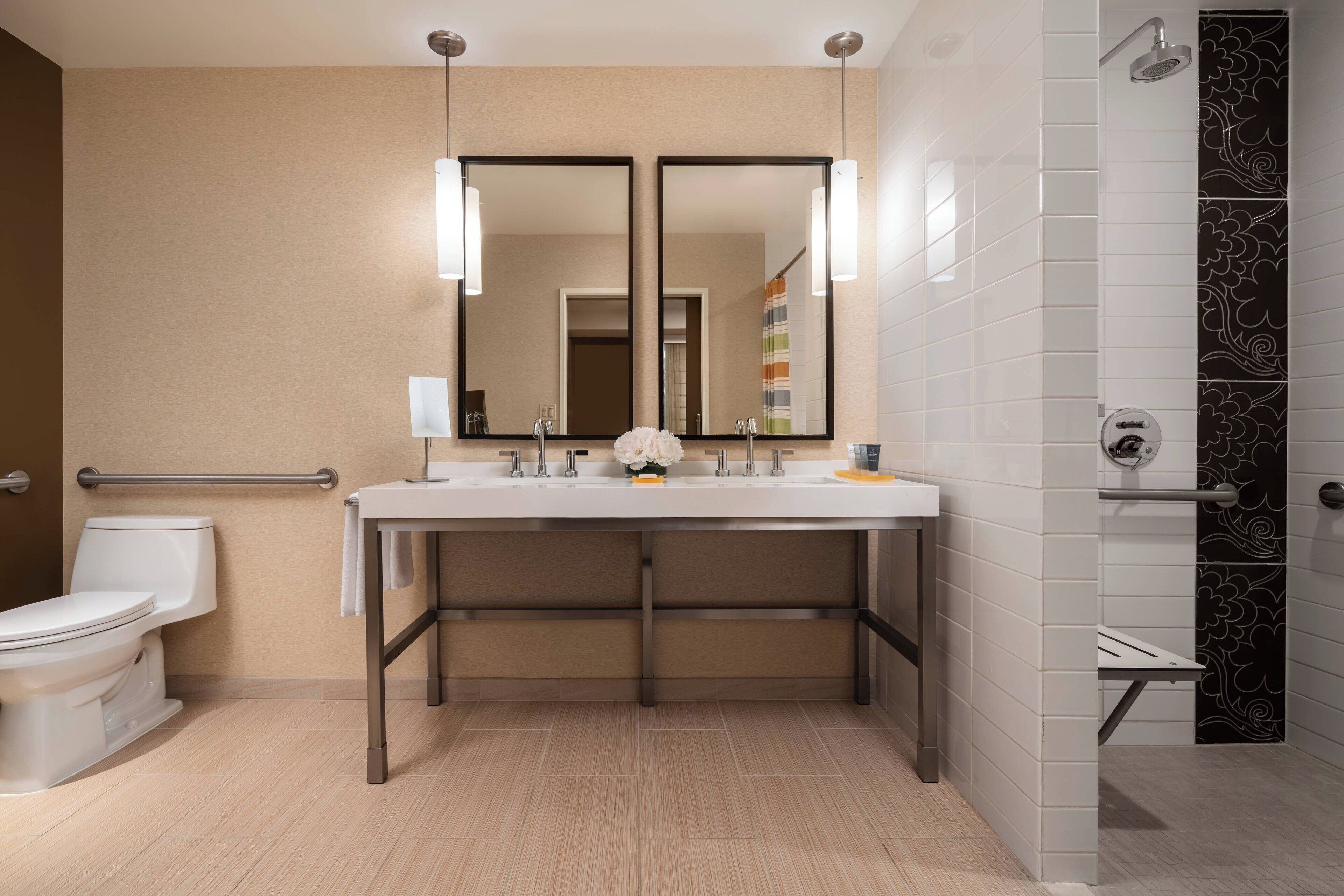 A modern bathroom with a white sink, two mirrors, a toilet, and a shower area.