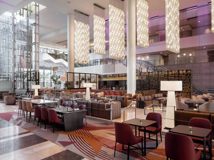 A spacious lobby with high ceilings, modern furniture, and a central staircase.