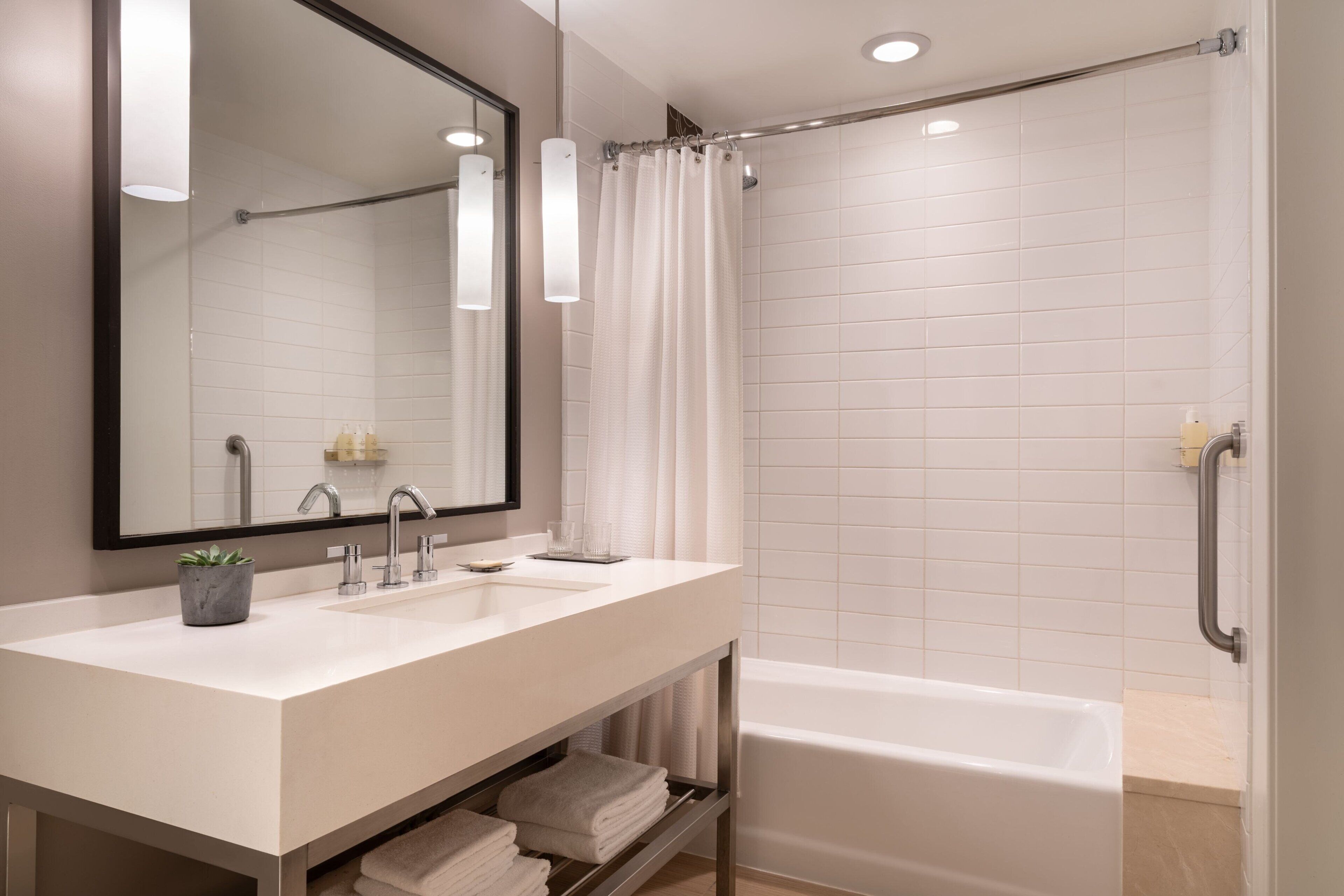 A modern bathroom with a white sink, mirror, and bathtub.
