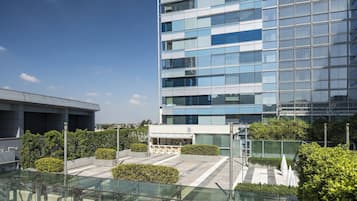 Een modern gebouw met een glazen gevel, een dakterras met zitplaatsen en een heldere lucht.