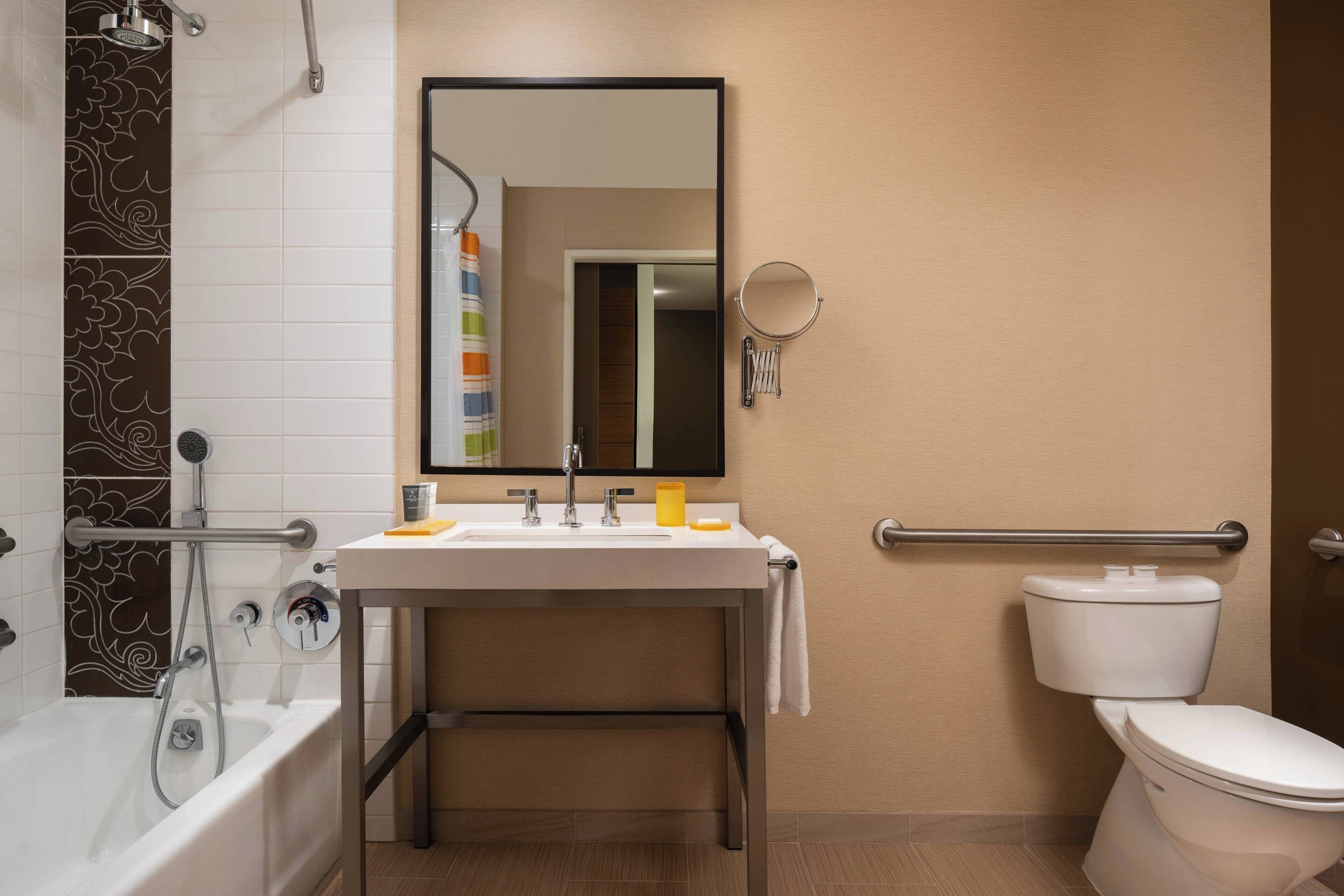 A modern bathroom with a bathtub, sink, mirror, and toilet.
