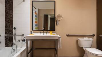 A modern bathroom with a bathtub, sink, mirror, and toilet.