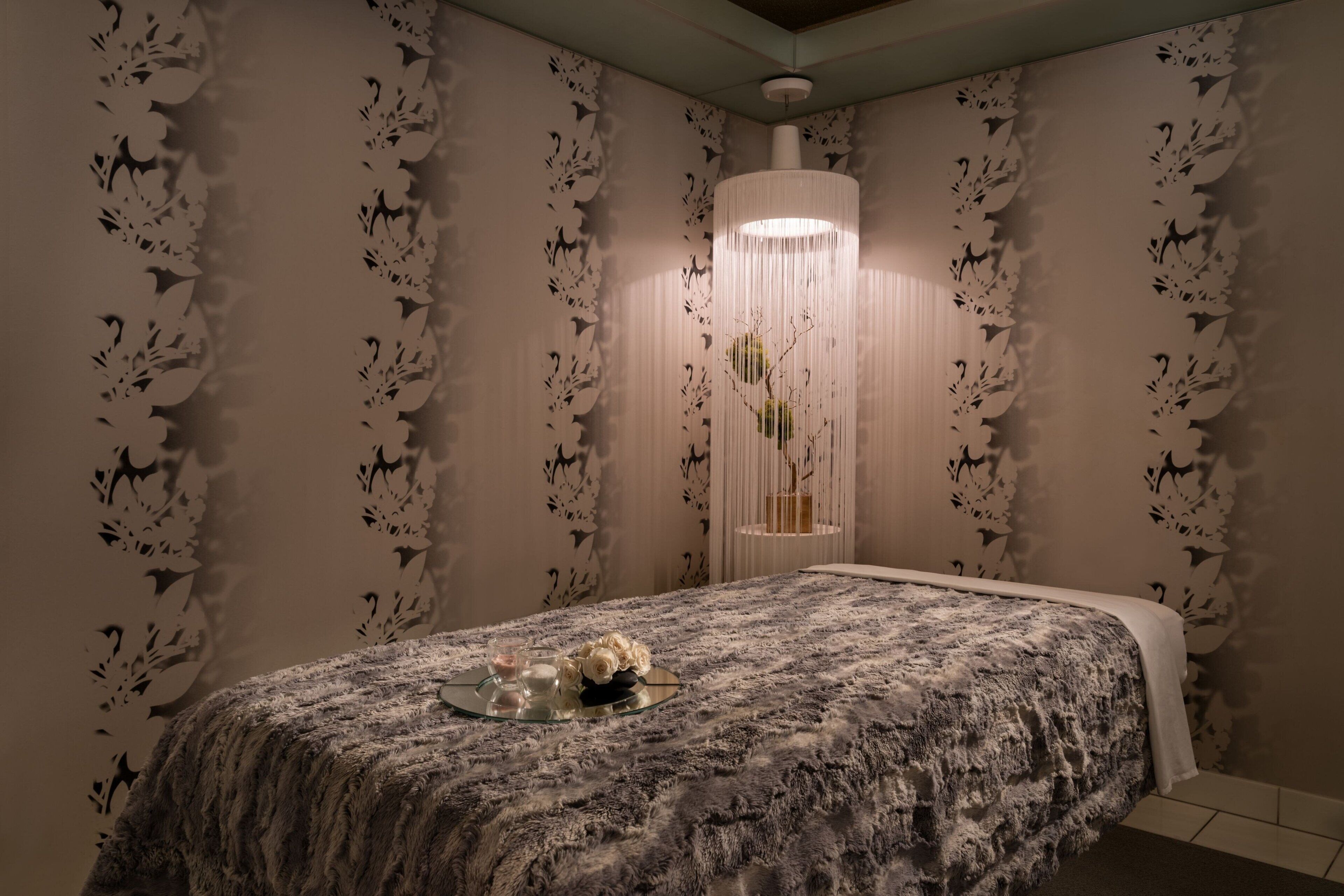 Une chambre à coucher avec un grand lit, un panneau décoratif au mur et un luminaire suspendu.