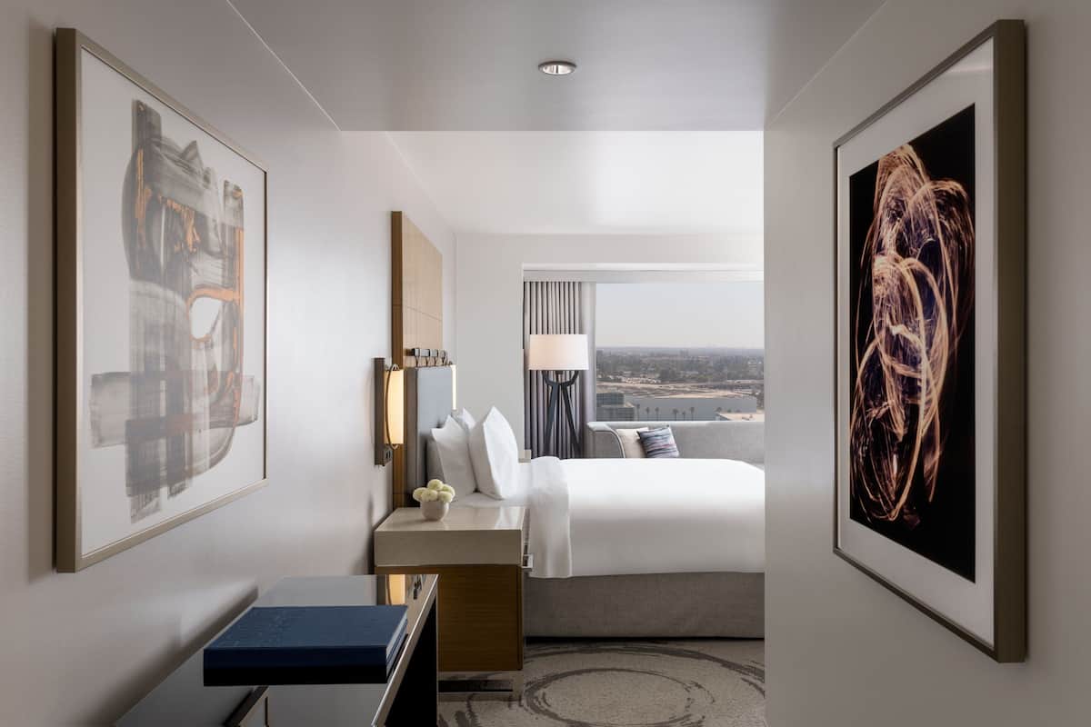 Une chambre d’hôtel avec un lit, une table de chevet, une lampe et des œuvres d’art accrochées aux murs.
